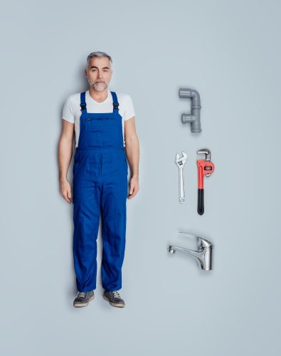 Realistic plumber toy doll with plumbing and house repair tools, flat lay